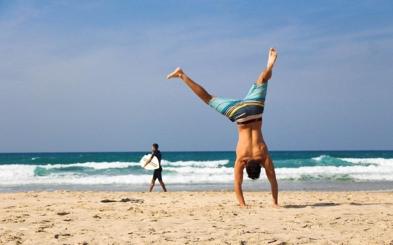 man doing a handstand on the beach