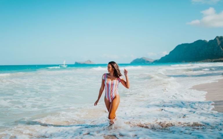 woman in a multicolored swimsuit walking on a beach